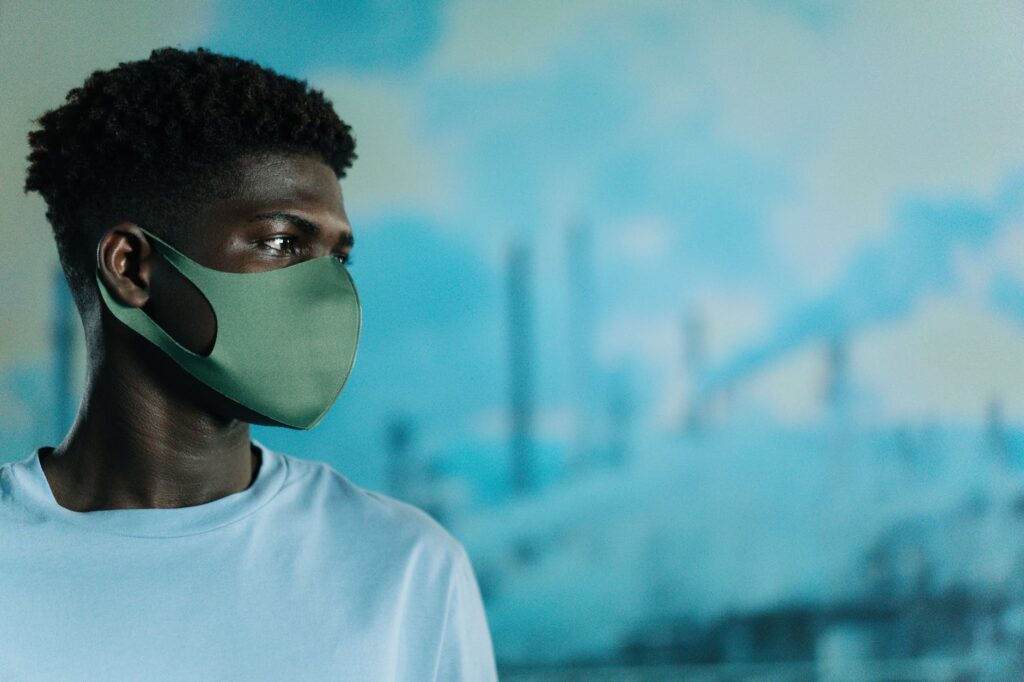 man in white crew neck shirt wearing a face mask as Intersectional Environmentalist author Leah Thomas talks about climate change