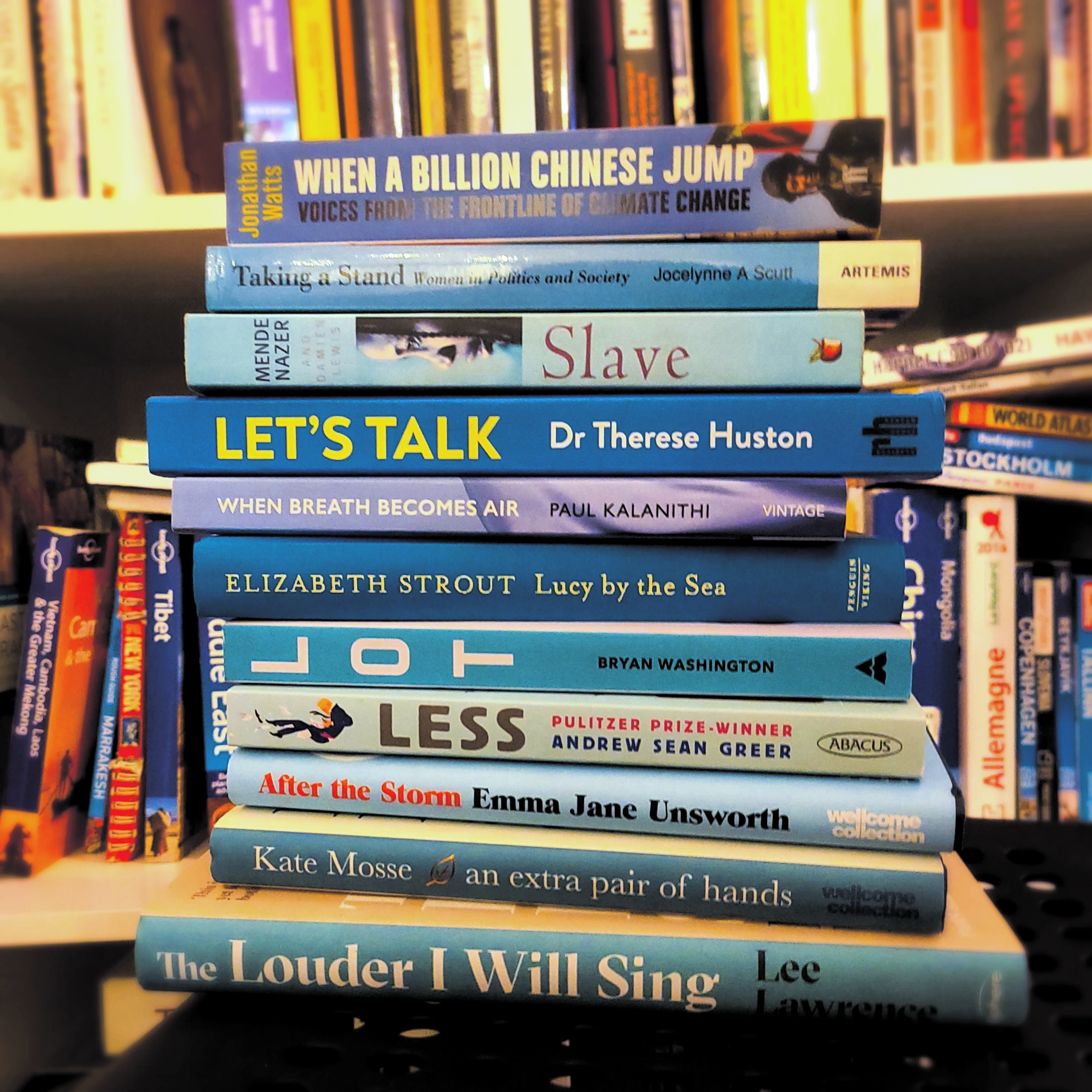 Stack of blue books with bookshelf behind