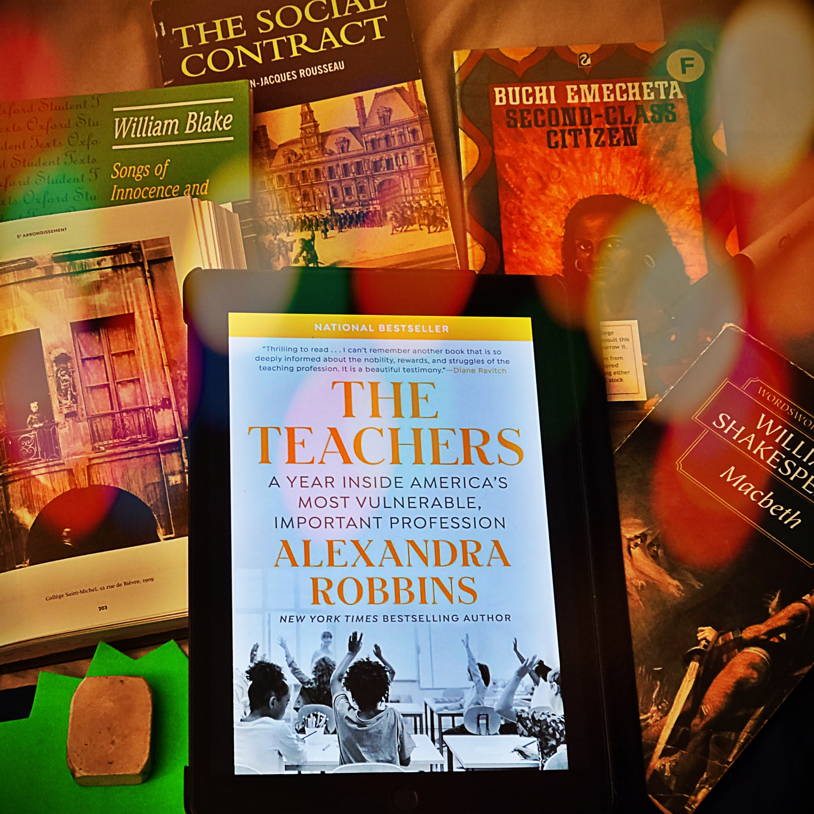 The Teachers by Alexandra Robbins seen surrounded by books including The Social Contract by Jean Jacques Rousseau, Second Class Citizen by Buchi Emecheta, Macbeth by Shakespeare, William Blake's poetry collection Songs of Innocence and Experience, black and white photo of a child in school in Paris in 1909 by Eugène Atget and stationery 