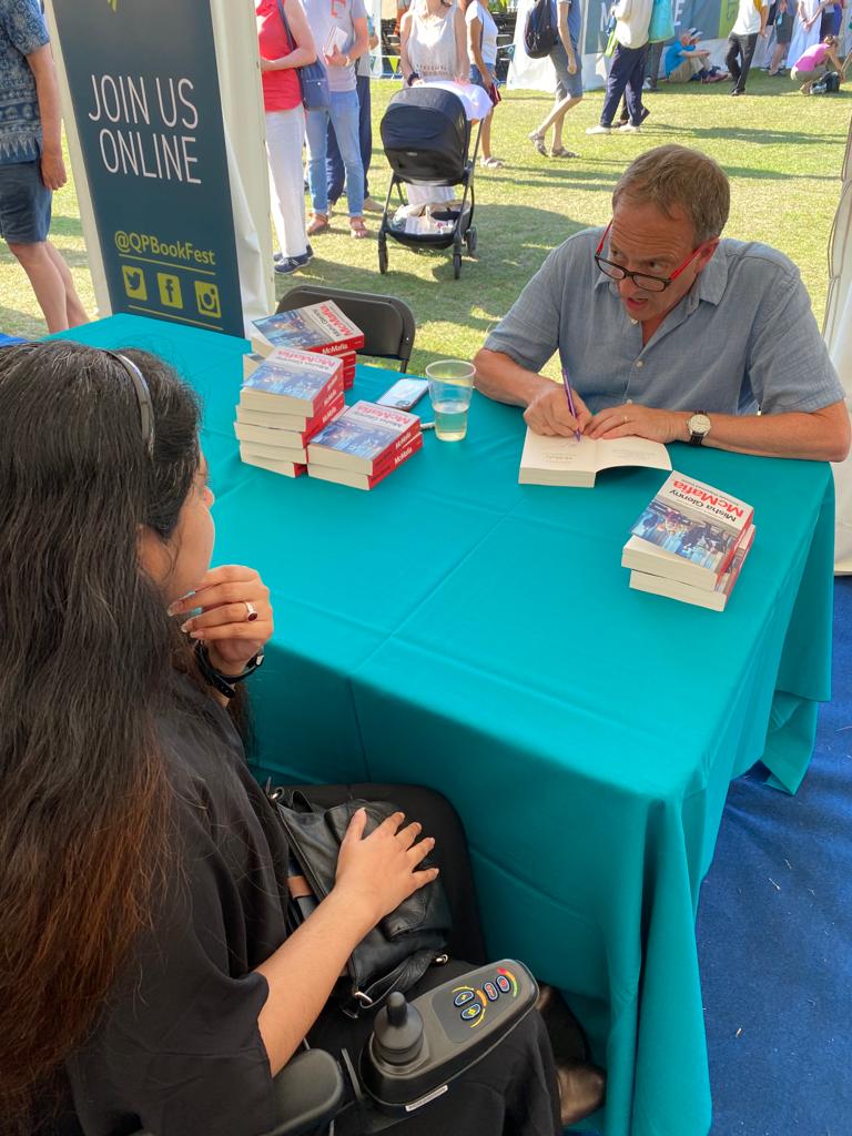 Suswati Basu speaking from her wheelchair to author and journalist Misha Glenny about foreign politics as he signs books McMafia.