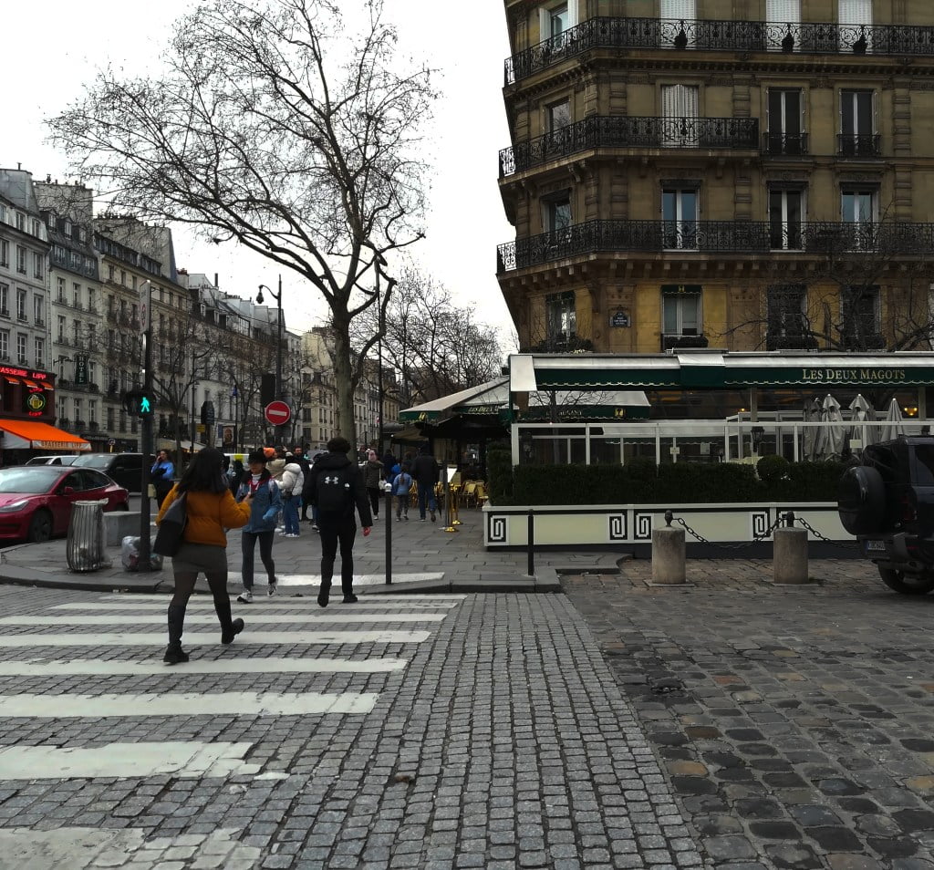 People walking past Le Deux Magots cafe. Paris literary tour