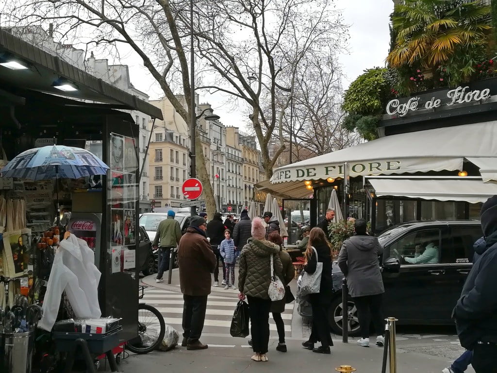 People walking past Cafe de Flores in Paris. Paris literary tour