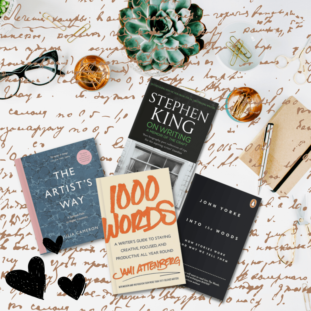 White desk with books including "1000 Words" by Jami Attenberg; "The Artist's Way" by Julia Cameron"; "Into The Woods" by John Yorke; and "On Writing" by Stephen Kings. Handwriting and heart doodle, with pen, notebook, paperclips, spectacles, and plant on desk.