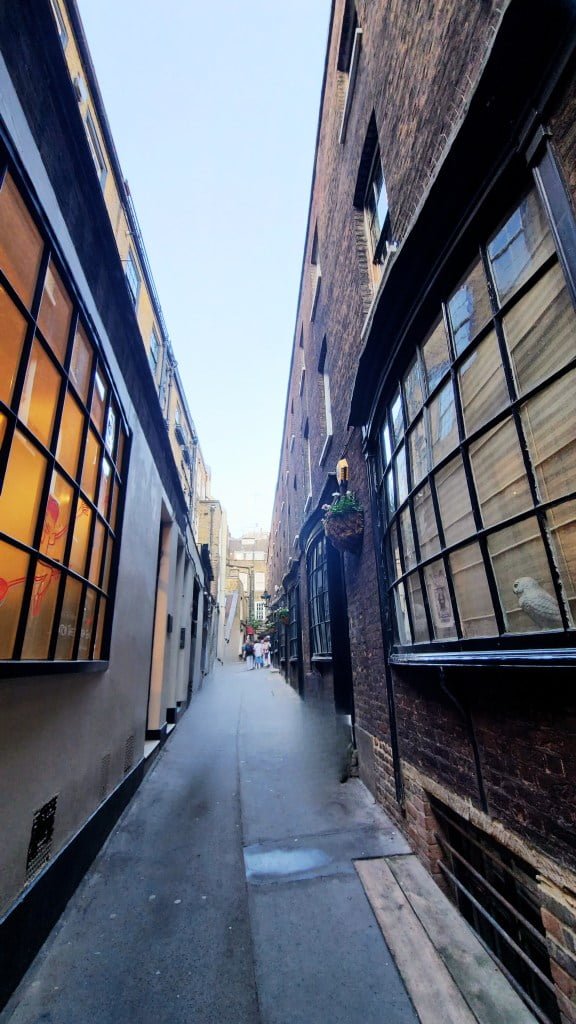 Harry Potter Diagon Alley Goodwin's Court in walking tour. A narrow, cobblestoned alley lined with historical buildings, giving a glimpse into a quieter, more quaint side of the city. This alleyway invites exploration and seems to whisper stories of the past with every footstep echoing off its walls.