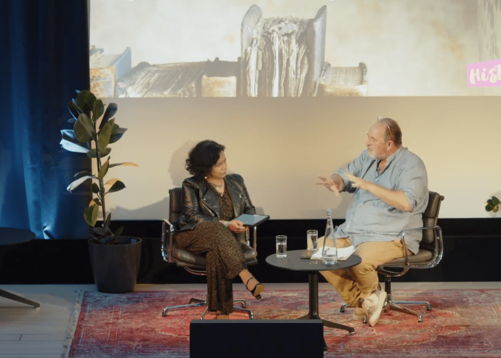 Nandini Das and William Dalrymple engaged in a panel discussion at HistFest 2024, with a decorative plant beside them.